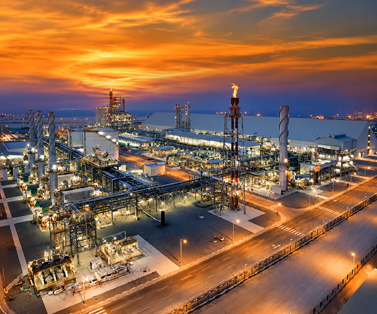 Industrial City of Abu Dhabi (ICAD): industrial plant with process units and a flare stack at sunset